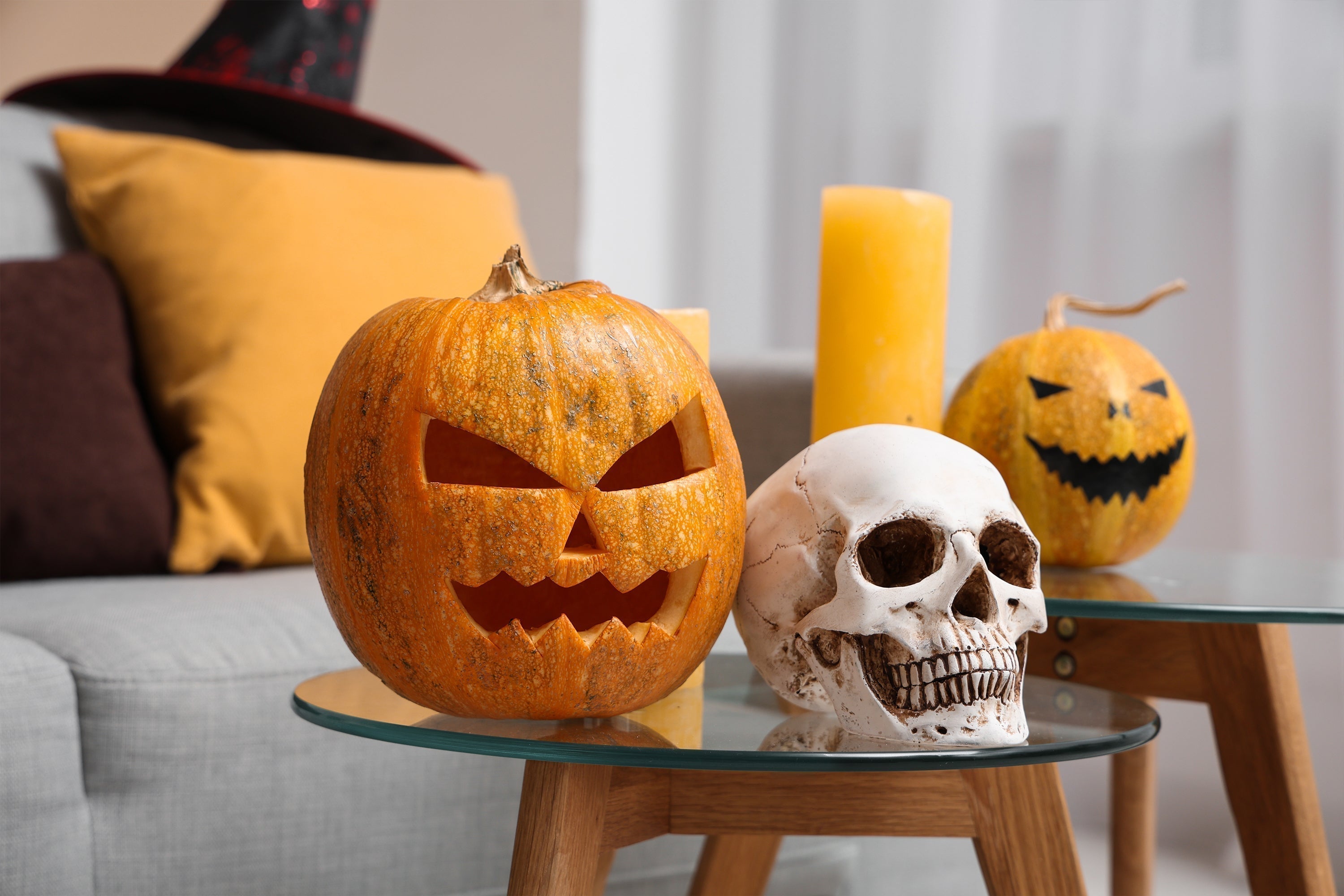 a close-up of Halloween decorations featuring a carved jack-o'-lantern, a realistic-looking skull, and yellow candles