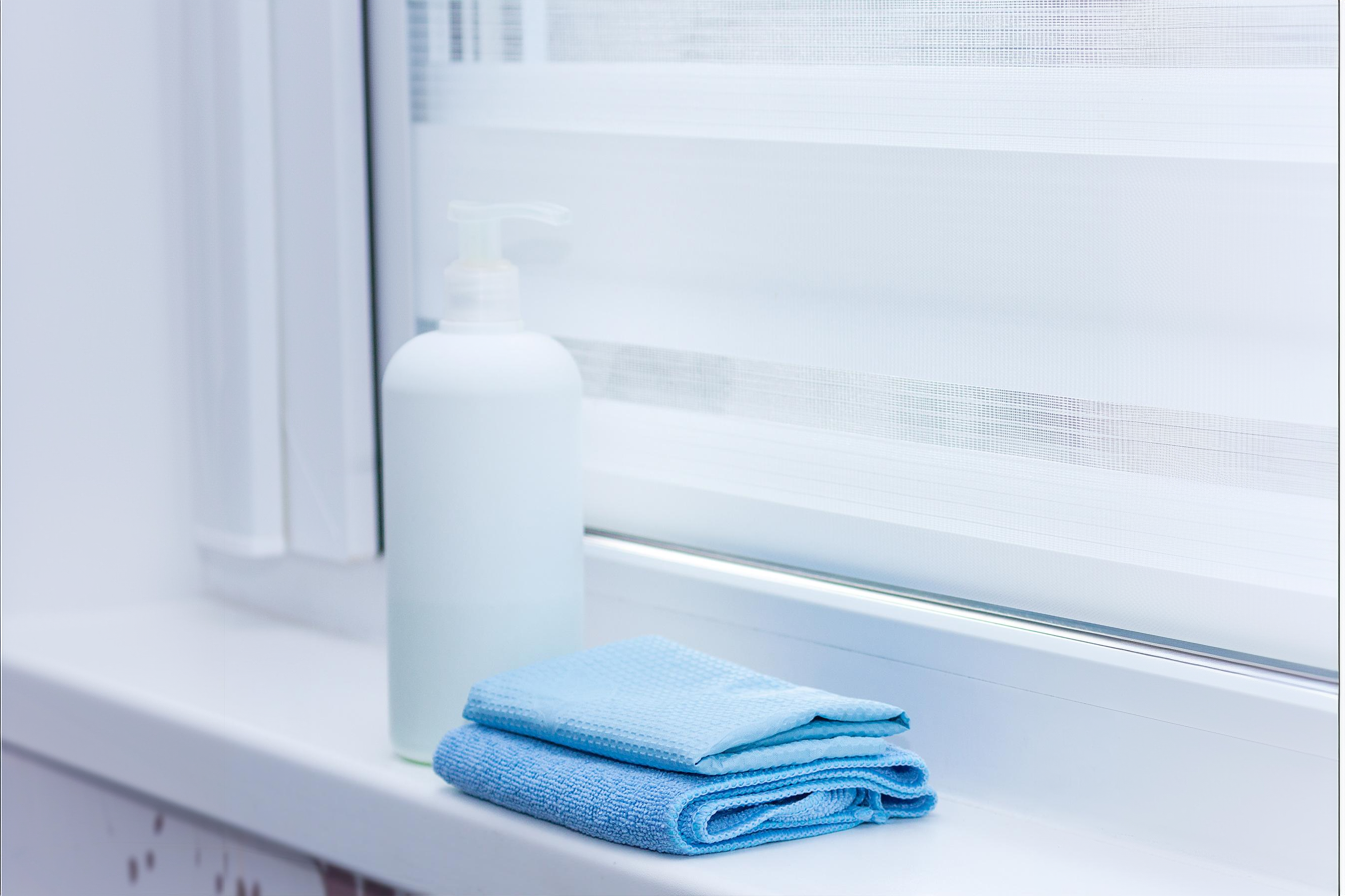 a mild cleaning solution and a microfiber cloth beside a zebra shade